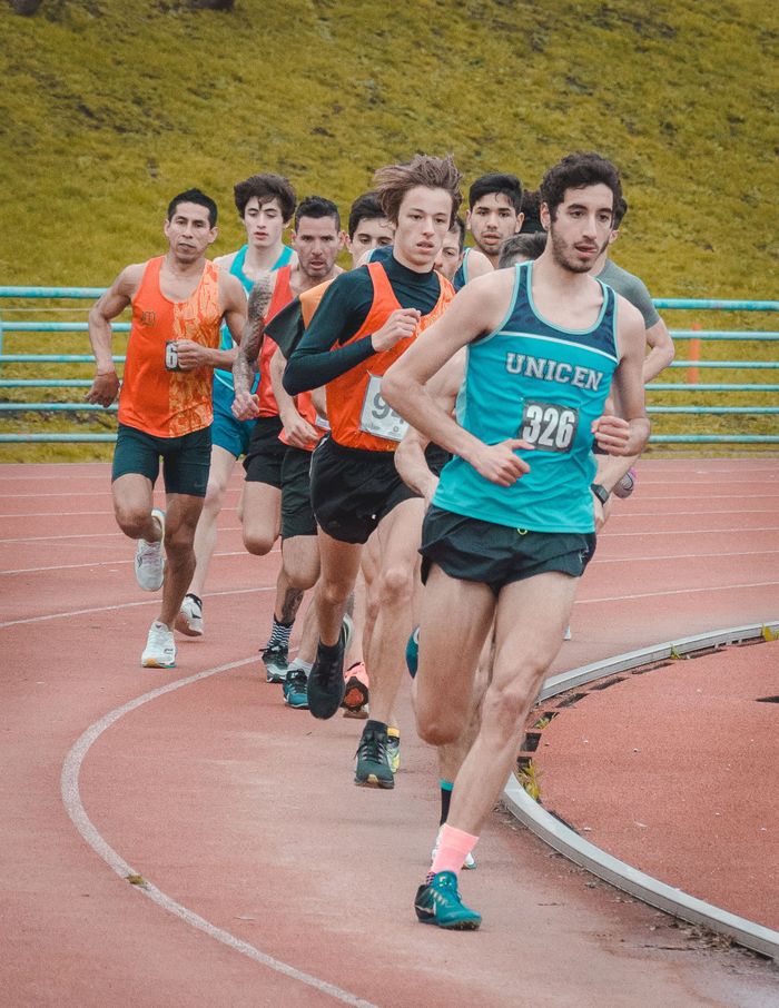 Group of male athletes in a race on an outdoor track, showcasing speed and competition.