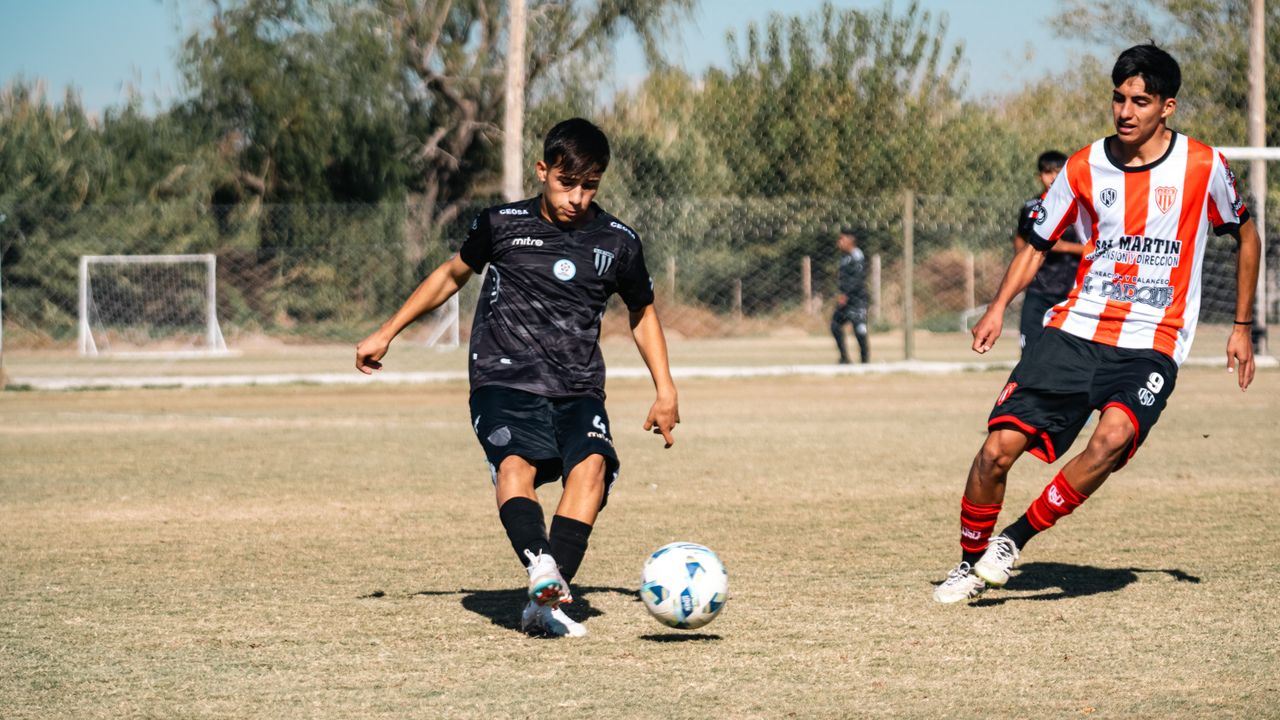 Two young soccer players compete in a game on an outdoor field, captured during the day.